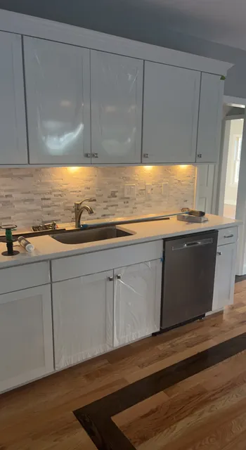 Remodeled kitchen with white cabinets and refinished hardwood flooring