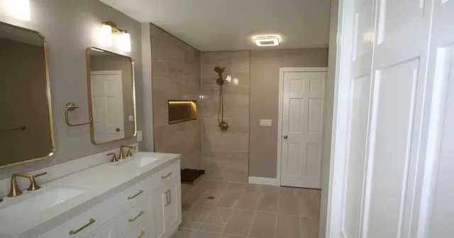 Spacious modern bathroom with double vanity, large mirrors, walk-in shower, and white cabinetry.