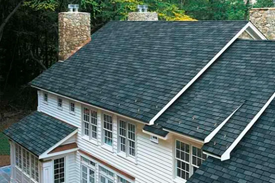 A large white house with a black roof and chimneys.