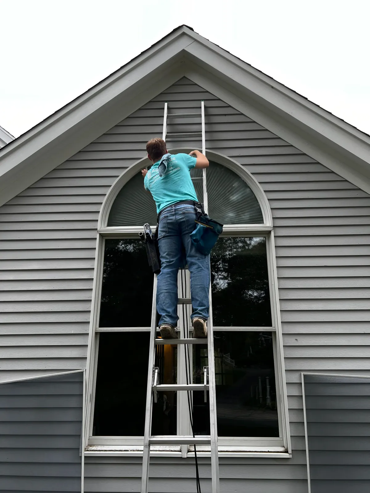 Worker on ladder cleaning window