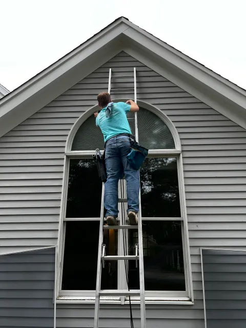 Worker on ladder cleaning window
