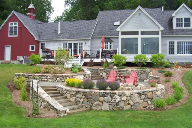Stacked stone walls surround a new fire pit area with fresh plantings