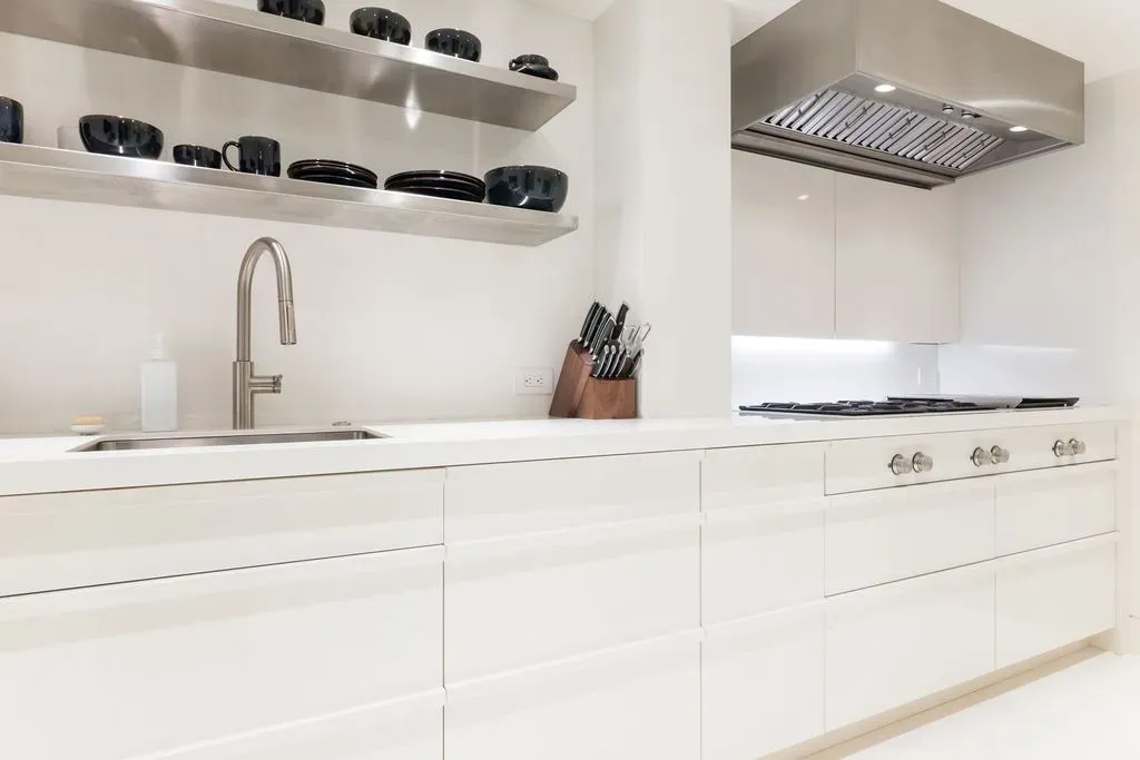 Bright white modern kitchen with cabinets, open shelves, sink, and stovetop