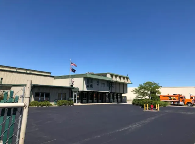 Industrial building with Canadian flag and parked orange truck under a clear blue sky