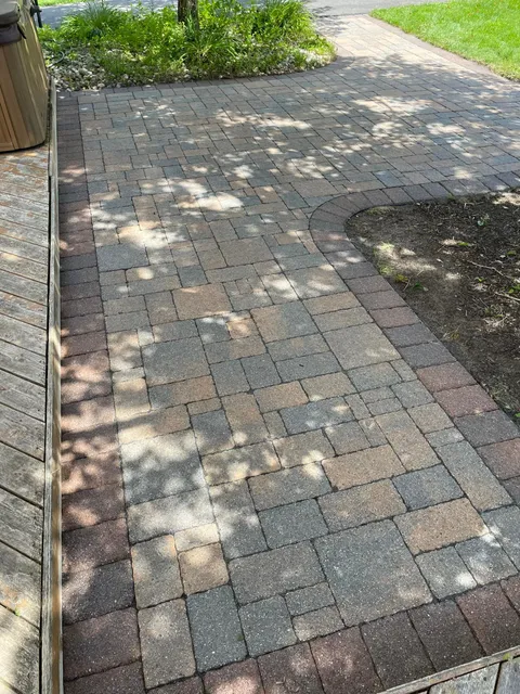 A brick walkway with a wooden deck in the background.