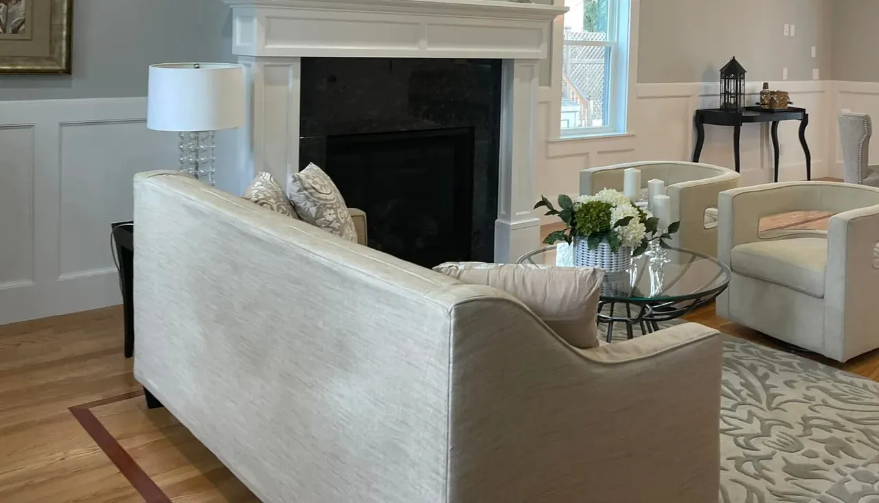 Living room with a fitted mantel and panel millwork running along the wall