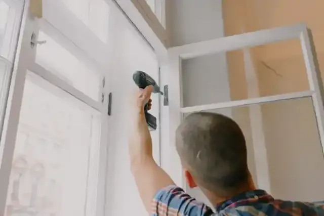 Man installing a window with a power drill, showcasing professional craftsmanship in window installation services.