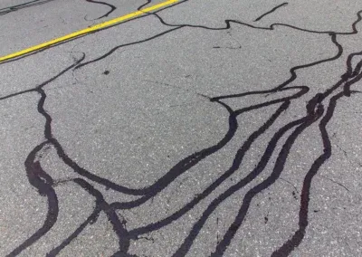 Cracks in asphalt pavement sealed with black crack filler on a roadway