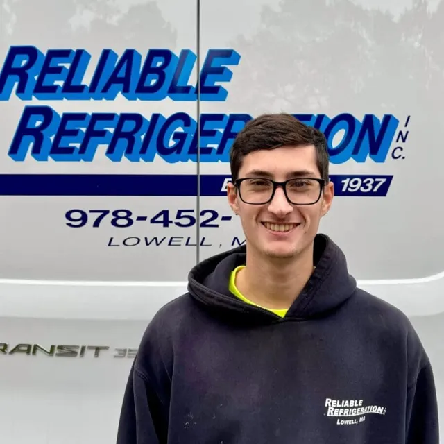 Technician smiling in front of Reliable Refrigeration truck.