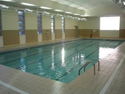 Indoor swimming pool with tiled deck, large windows, and a projection screen at the far end.