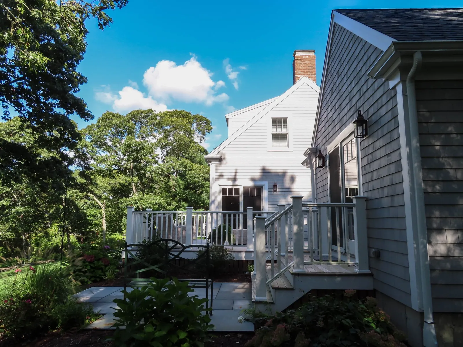 A back deck with painted white railings and stairs to a patio in the yard