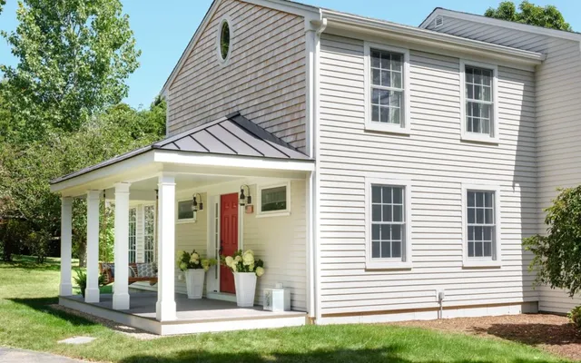 Two-story beige house with white trim, red door, porch, green yard – Woodland Builders, South Shore MA.