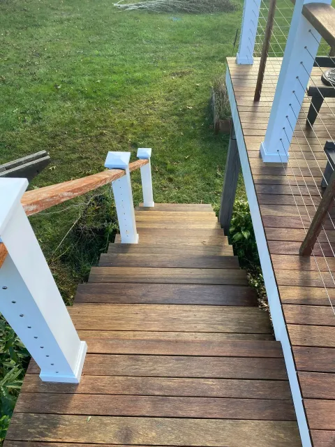Wooden outdoor staircase with white railing posts leading down to a grassy yard.