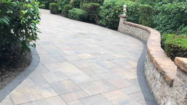 Curved paver walkway edged by a natural fieldstone wall