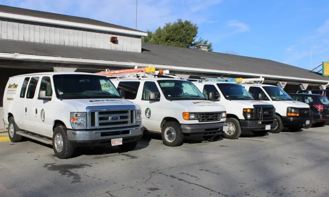 Pickup trucks parked in front of a building, with a ladder and equipment on top, under a clear blue sky.