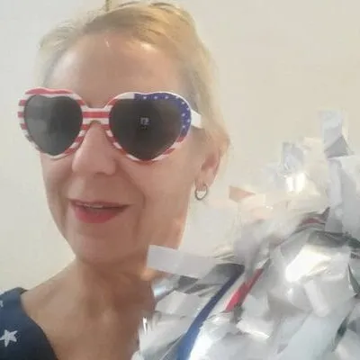 Woman wearing sunglasses and holding a gift with a silver bow.
