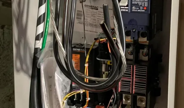 Inside view of an open Generac transfer switch with electrical wiring and a 200A circuit breaker.