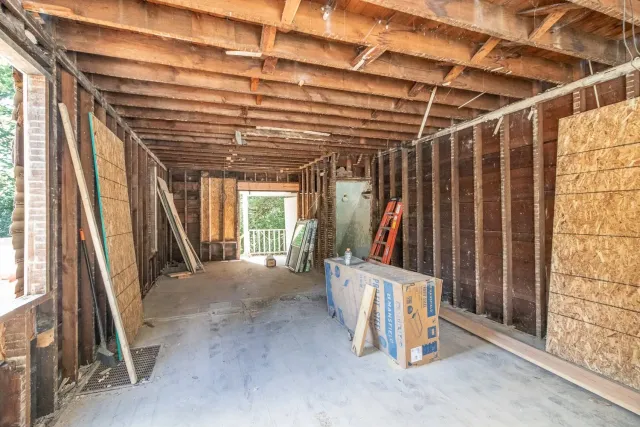 Interior gut renovation showing exposed wood framing and subfloor during home remodel