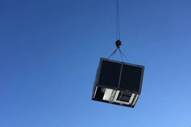 A crane is lifting a piece of equipment into the air.