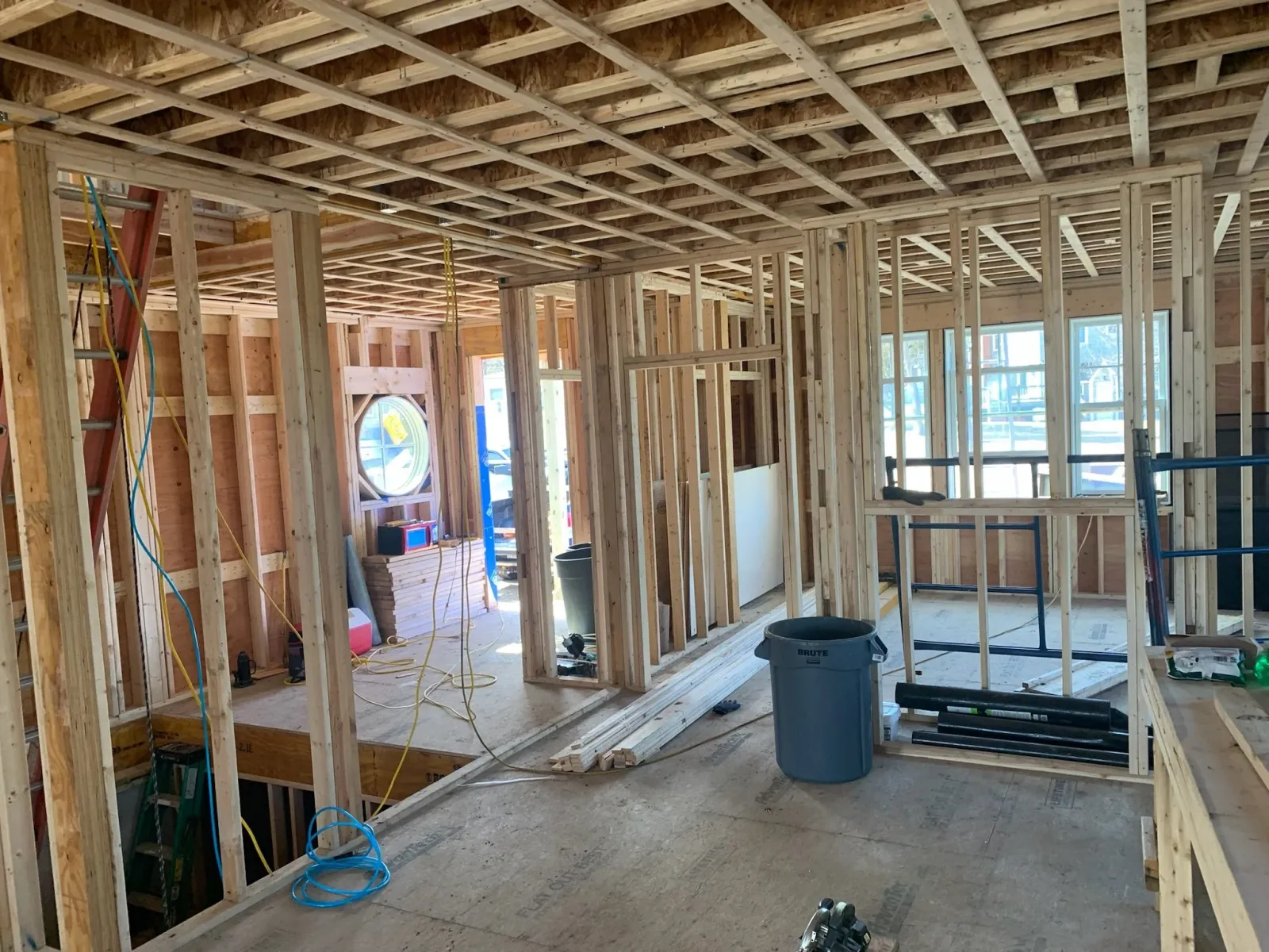 Interior view of a house under construction with exposed framing, wooden studs, and unfinished walls, with construction tools and materials scattered around. Scituate, Norwell, Hanover, Hanson, Marshfield, South Shore. Massachusetts Local.