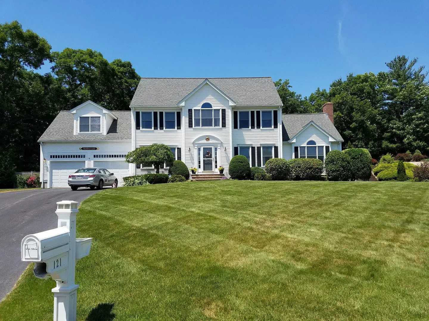 Colonial with a striped front lawn and mailbox planting