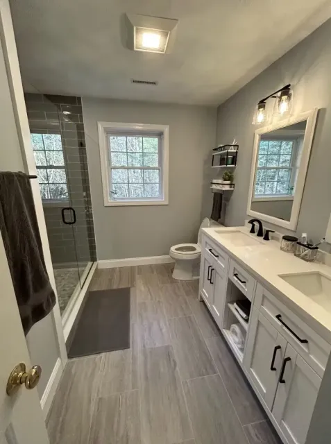 A bathroom with two sinks, a toilet, and a walk-in shower.