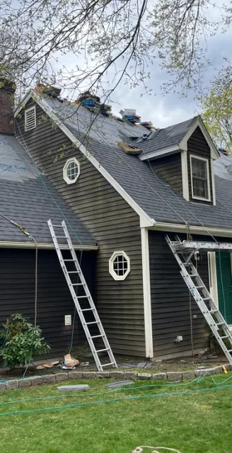 Professional residential roof replacement in progress with new shingles, underlayment, and ladders.