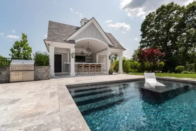 Modern house with covered patio and blue swimming pool in a landscaped backyard