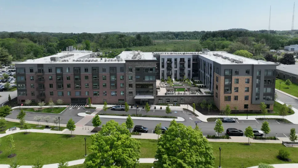 An aerial view of a large apartment building with a lot of cars parked in front of it.