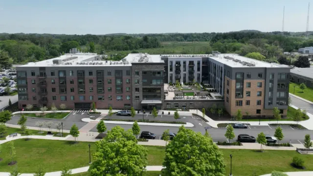 An aerial view of a large apartment building with a lot of cars parked in front of it.
