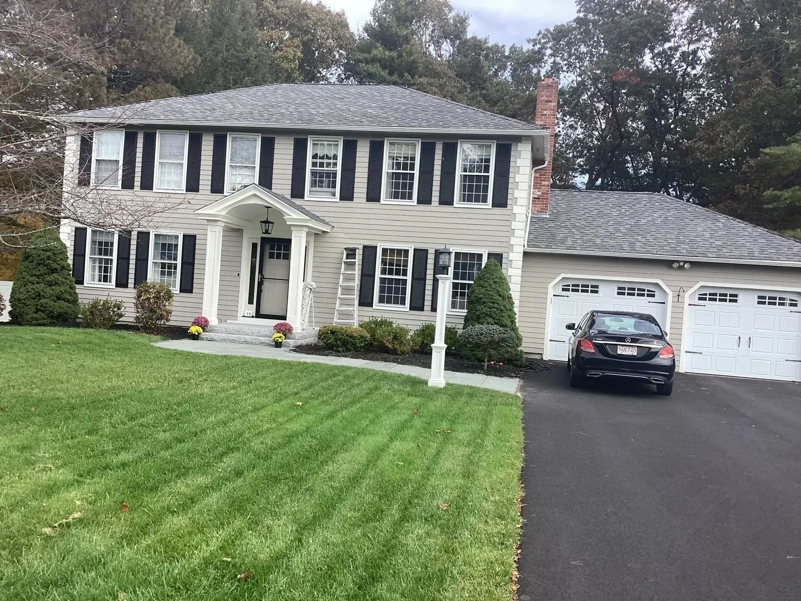 Two-story suburban house with black shutters, white trim, and a car parked in the driveway