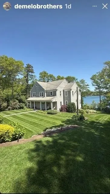 White house with manicured lawn and lake view under a clear blue sky