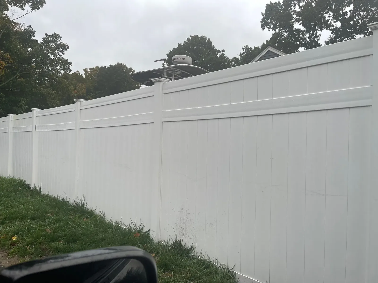 A white fence is sitting on top of a lush green field.
