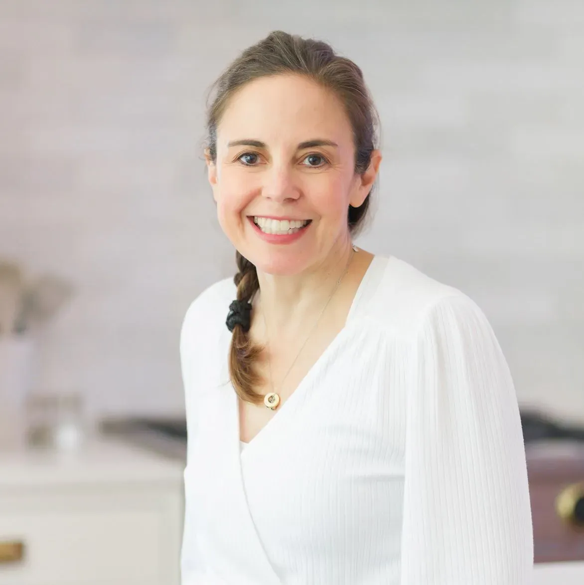 Smiling woman in a white top in a bright kitchen