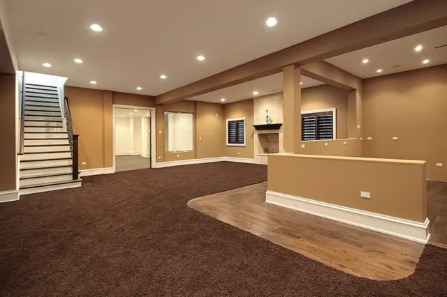 Empty finished basement with carpeted living area, stairs, recessed lights, and a small bar counter.