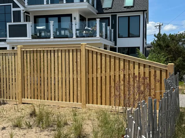 A wooden fence is in front of a large house.