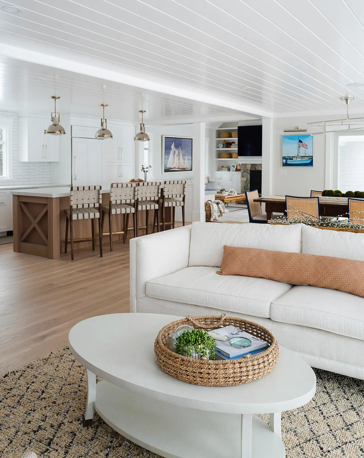 Hardwood floor installation in a Plymouth open-concept living area with white furniture, nautical decor, sailboat artwork, a built-in bookshelf, TV, and a dining table.
