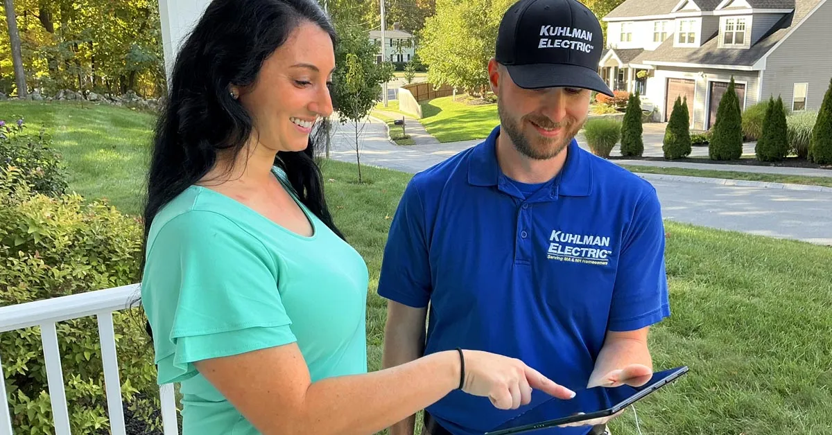Kuhlman Electric electrician reviewing project details with a homeowner on a tablet.