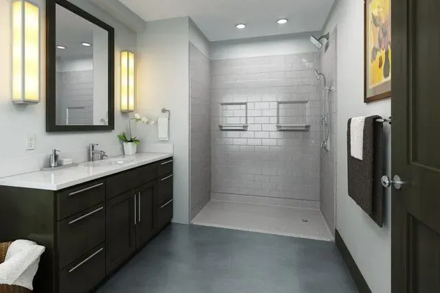Modern bathroom with black vanity, white sink, gray tile shower, and wall mirror lights