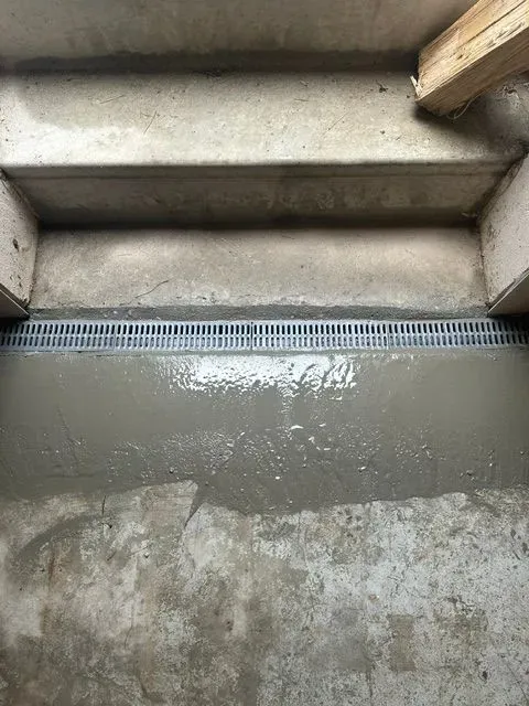 Concrete steps with a wet landing and a grated drain at the bottom