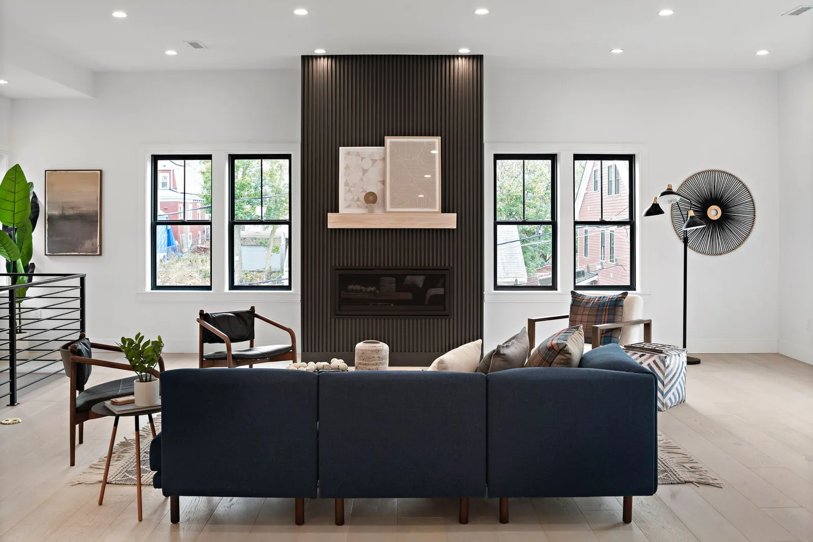 Living room with wood flooring, fireplace, views of outside. Lot of blue upholstery and artwork hanging on the walls. Note...
