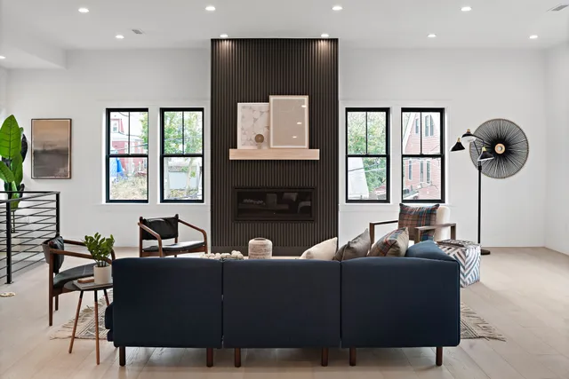 Living room with wood flooring, fireplace, views of outside. Lot of blue upholstery and artwork hanging on the walls. Note...