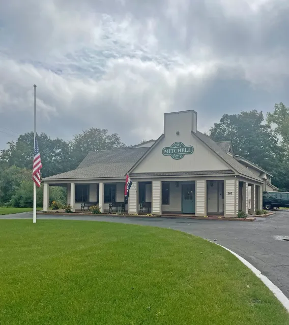 A small white house with an american flag in front of it