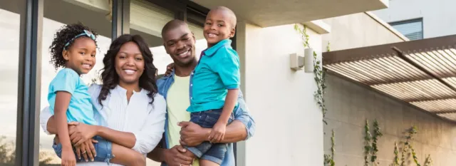 Smiling family standing outside their new home after a successful move with an NYC moving company.