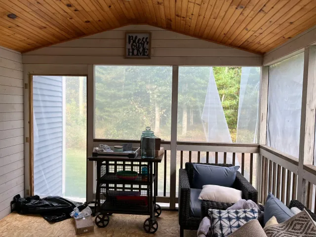 A screened in porch with a chair and a cart.
