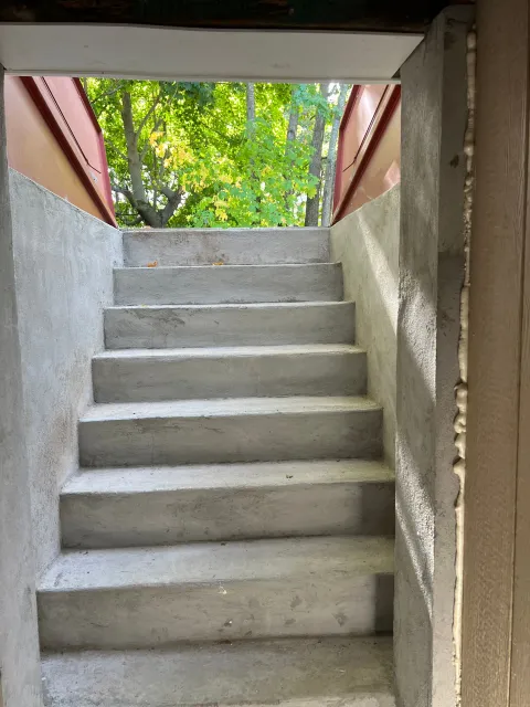 Concrete stairs lead up to an opening with trees visible in the background