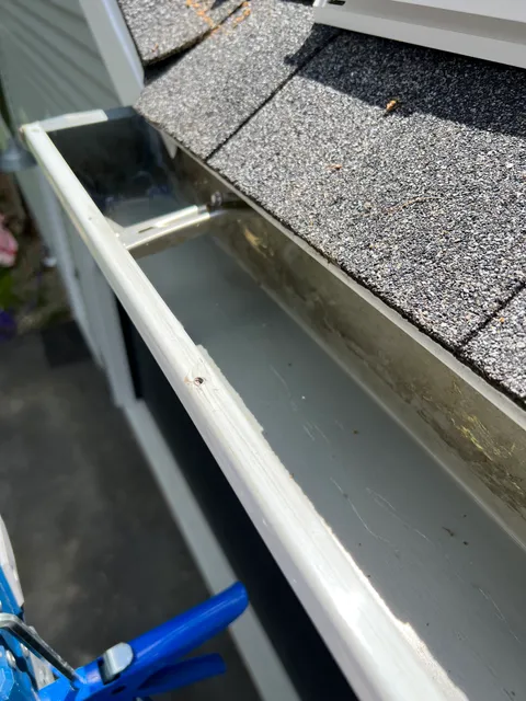 Close-up of fresh white K-style seamless gutter during installation