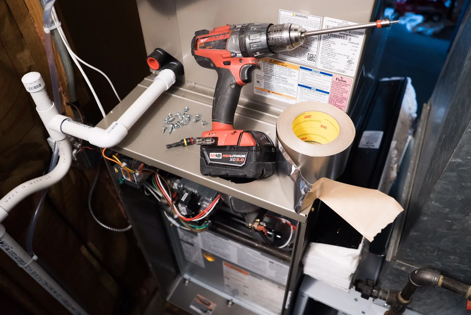 HVAC technician installing high-efficiency furnace with tools and supplies.