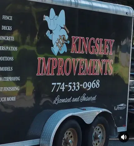 Black trailer with Kingsley Improvements logo, phone number, and exterior home improvement services listed on the side