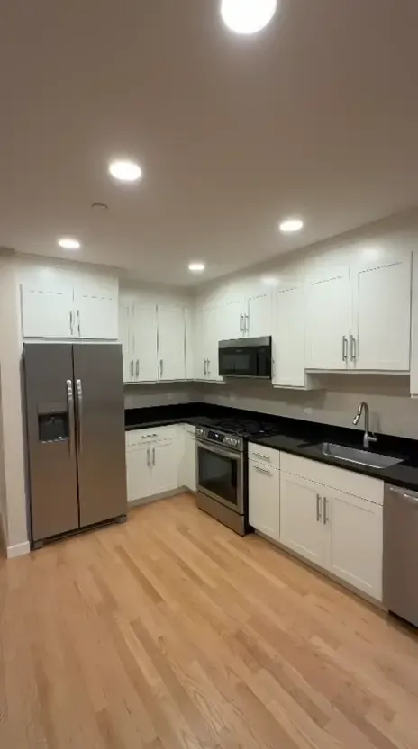 A completed white kitchen with dark countertops and a clean finished-cabinet presentation.